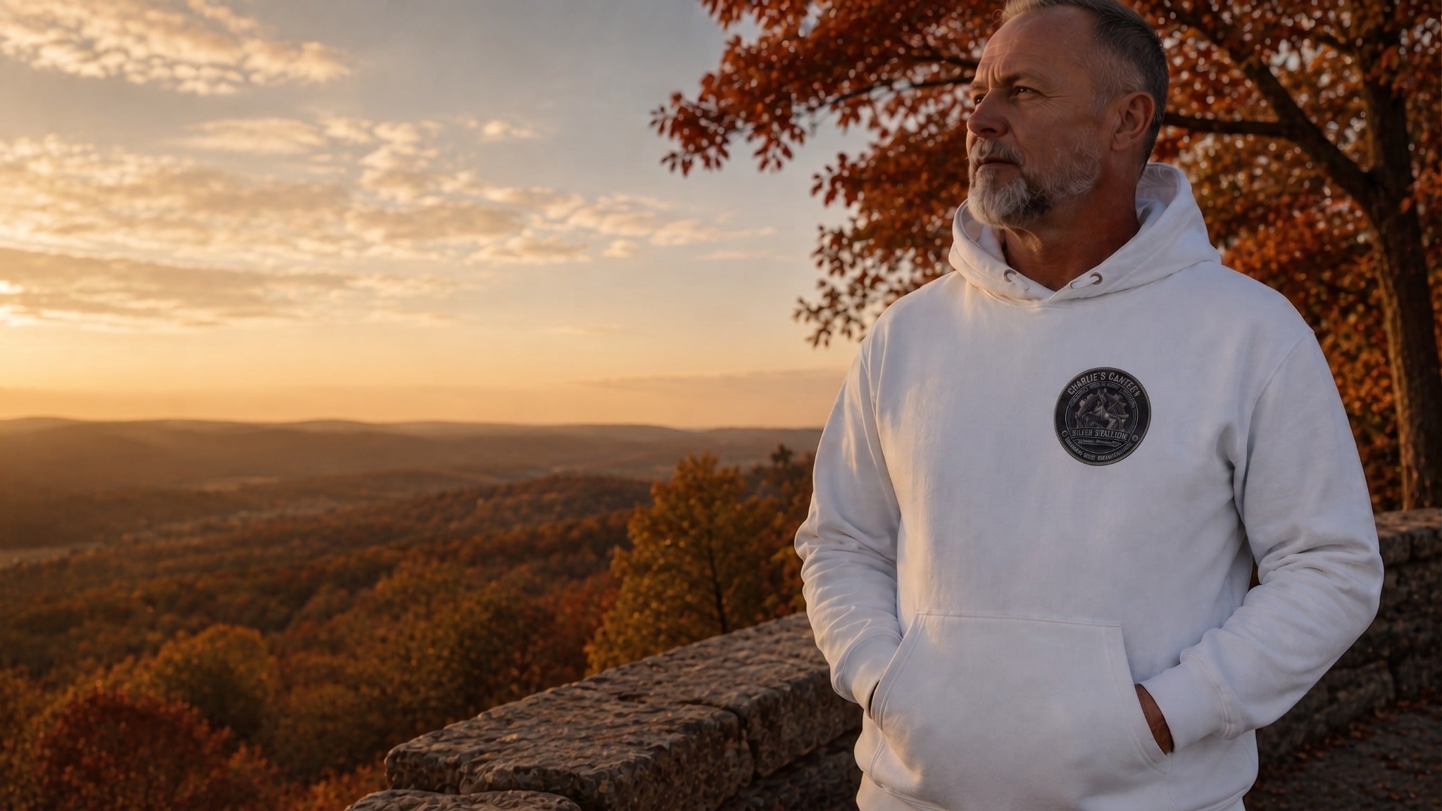 Older man wearing a white Charlie's Canteen Silver Stallions hoodie with a restrained small chest emblem at an autumn overlook